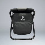 A black Valour cooler bag chair with a steel frame, featuring a cushioned seat and a large front pocket, displayed against a grey background.